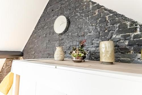 a white table with a clock on a brick wall at Spacious Shared 5BR Apt in the Heart of Gent in Ghent