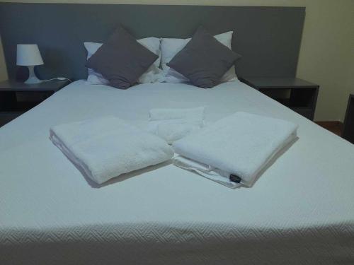 a white bed with three white towels on it at Hotel Jorge V in Mirandela