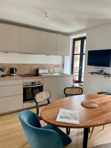 une cuisine avec une table en bois et des chaises bleues dans l'établissement L'éclipse - T4 sur le port du Pouliguen, au Pouliguen
