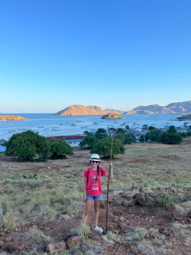 a woman standing next to a pole in a field at Jhuna Komodo Homestay in Komodo