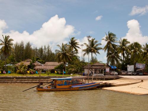 un barco está atracado en un muelle en un río en Casacool Hotel, en Khao Lak