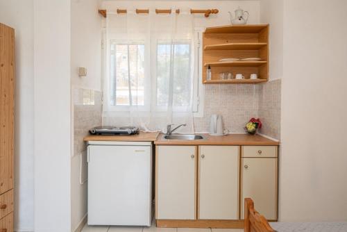 a kitchen with white cabinets and a sink at Fiore Di Mare Studios in Lassi