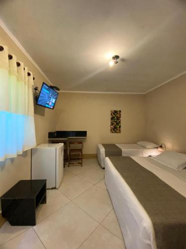 a hotel room with two beds and a flat screen tv at Pousada Sol e Cia Tur in Caraguatatuba