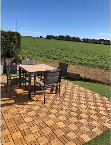 - une table et des chaises sur une terrasse avec un champ dans l'établissement La villa Pontivyenne, à Noyal-Pontivy