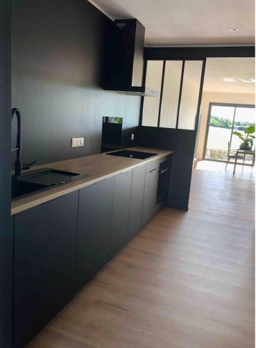 une cuisine avec des armoires noires et un plancher en bois dans l'établissement La villa Pontivyenne, à Noyal-Pontivy