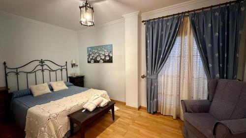 a bedroom with a bed and a chair and a window at Hotel El Curro in Burunchel