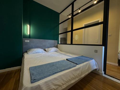 a bed in a room with a green wall at Gigi Apartment by eluxory in Skopje