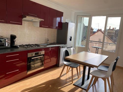 une cuisine avec des armoires rouges et une table avec des chaises dans l'établissement Chez Julien, à Troyes