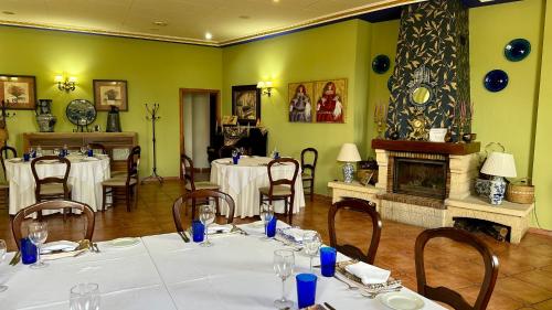 a dining room with tables and chairs and a fireplace at Hotel El Curro in Burunchel