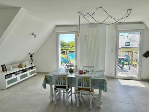 a white dining room with a table and chairs at Appartement près de la mer in Larmor-Plage