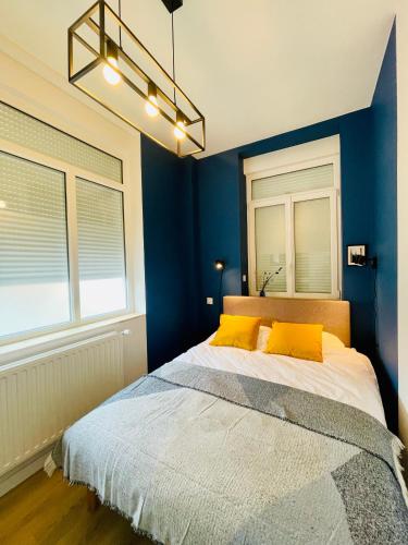- une chambre avec des murs bleus et un lit avec des oreillers jaunes dans l'établissement Charming flat ideal location, 2 bedroom 5 pers max, à Lille