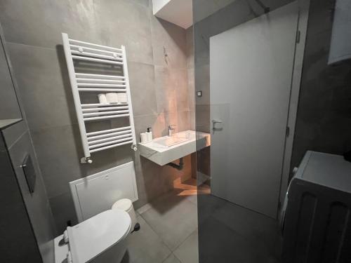 a bathroom with a white toilet and a sink at Gigi Apartment by eluxory in Skopje