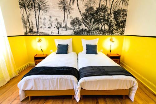 deux lits dans une chambre aux murs jaunes dans l'établissement Bel AMI 01 - Turquoise & OR - Moderne Chic - Centre Ville - Accès Jardin - Clim - Wifi - Parking - Localisation idéale, à Schiltigheim