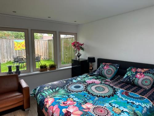 a bedroom with a bed with a colorful comforter and windows at Casa Delfts Blauw in Mierlo