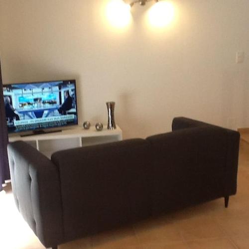 un salon avec un canapé et une télévision à écran plat dans l'établissement Maison jaune, à Aimargues