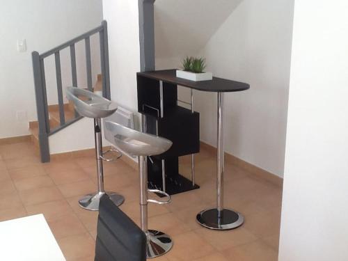 une table avec deux tabourets et une table avec une installation sur celle-ci, dans l'établissement Maison jaune, à Aimargues