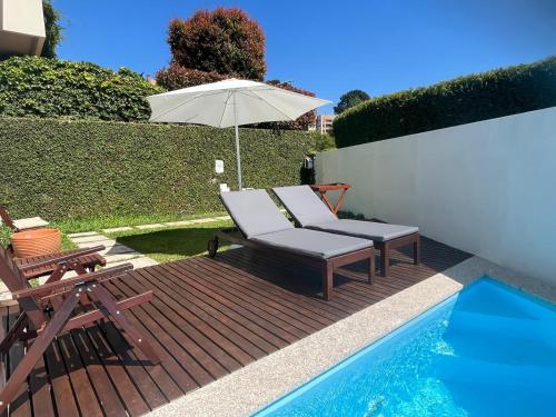 a deck with a chair and an umbrella next to a pool at Signature Guesthouse in Porto