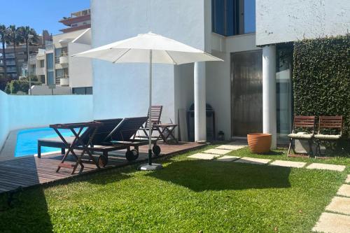 a patio with a table and an umbrella and chairs at Signature Guesthouse in Porto