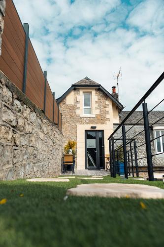 a house with a stone wall and a black door at Gîte les grandes lauzes in Espalion