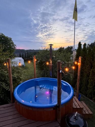 a hot tub on a deck with a sunset at Karmelowe Domki Kaszuby, z jacuzzi na tarasie z widokiem na jezioro in Stężyca