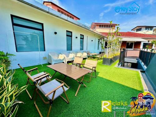 a patio with a table and chairs on the grass at Modern Cave Guest House Walking Distance 5Mins To Jonker in Melaka
