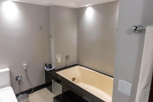a bathroom with a bath tub and a toilet at Plaza São Rafael Hotel in Porto Alegre