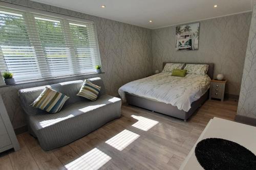 a bedroom with a bed and a couch and a window at Little Eden New Forest and Coastal Retreat Langley Hampshire in Langley