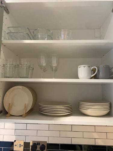 a kitchen shelf with plates and cups and glasses at Little Eden New Forest and Coastal Retreat Langley Hampshire in Langley