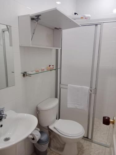 a white bathroom with a toilet and a sink at Hotel Cafetero Valparaíso in La Vega