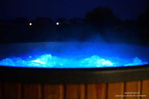 a blue fire with snow covered mountains in the background at Osada Aurora Całoroczne domki z jacuzzi z widokiem na jezioro i góry in Miszkowice