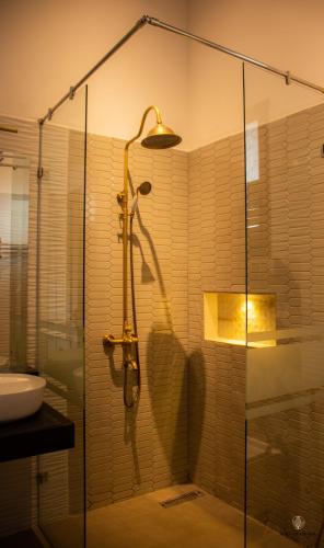 a shower with a glass door in a bathroom at Nirvana Bliss By Clove in Anuradhapura