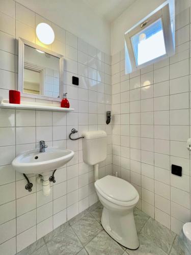 a white bathroom with a toilet and a sink at Muskatli in Zalakaros