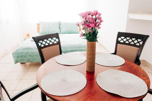 a wooden table with plates and a vase of flowers at Castle Village Apartment in Krásnohorské Podhradie