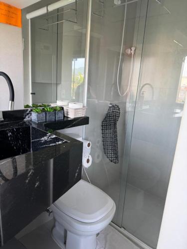 a bathroom with a toilet and a glass shower at Bombinhas in Bombinhas