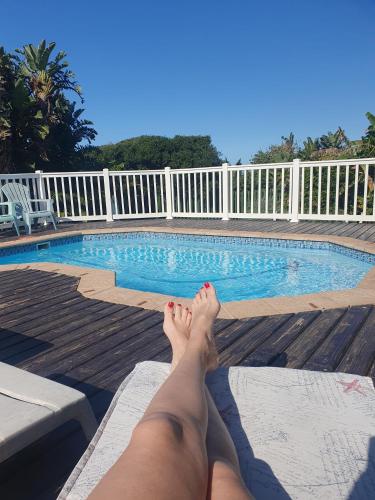 a person laying on a bench next to a swimming pool at Seagulls Beach House in Port Shepstone