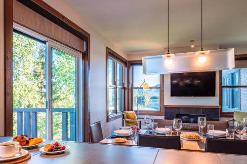 a dining room with tables and chairs and windows at Lakefront, Mountain View - 2 Bds Superior Resort Suite in Lac-Superieur