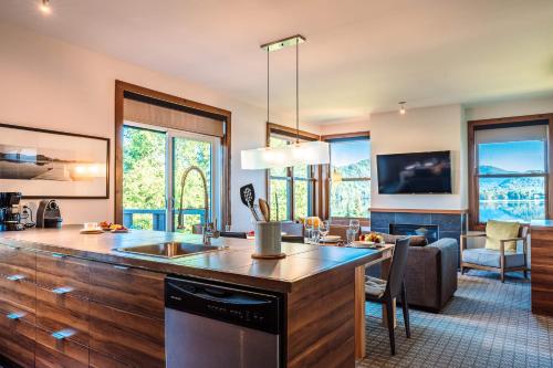 a kitchen with a sink and a living room at Lakefront, Mountain View - 2 Bds Superior Resort Suite in Lac-Superieur