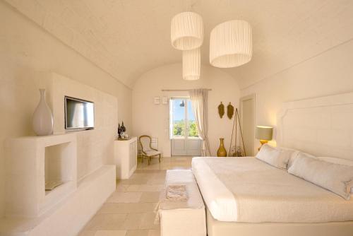 a white bedroom with a bed and a window at Masseria San Francesco in Savelletri di Fasano