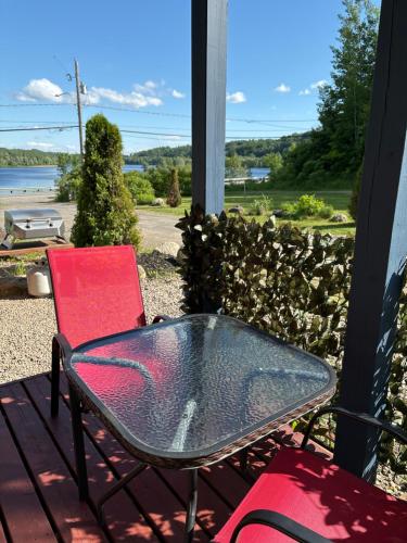 a table and chairs on a porch with a view of the water at Domaine de la Baie, Les Suites in Shawinigan