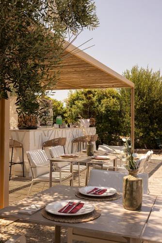 a patio with tables and chairs under a wooden canopy at Masseria San Francesco in Savelletri di Fasano