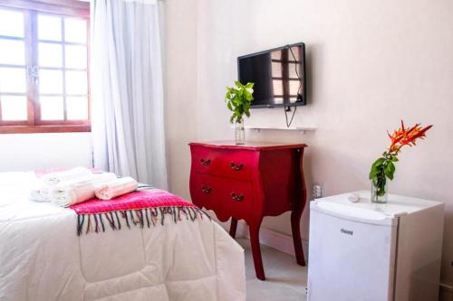 a bedroom with a red dresser and a television at Pousada Saruê Praia de Ponta Negra Natal RN in Natal