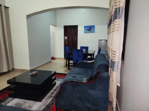 a living room with a blue couch and a table at Touch of Class and Simplicity in Kampala
