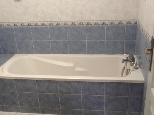 La salle de bains est pourvue d'une baignoire et de carrelage bleu. dans l'établissement Maison jaune, à Aimargues