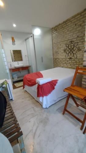 a bedroom with a large bed and a wooden chair at Pousada Saruê Praia de Ponta Negra Natal RN in Natal