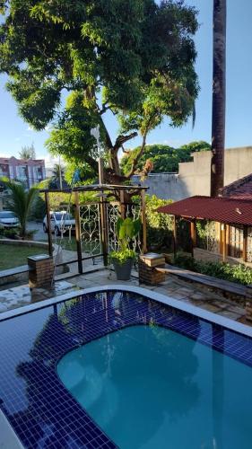 a swimming pool in a yard with a tree at Pousada Saruê Praia de Ponta Negra Natal RN in Natal