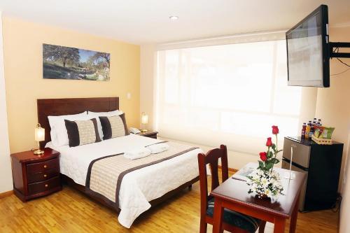 a bedroom with a bed and a table and a television at Hotel Xilon Pasto in Pasto