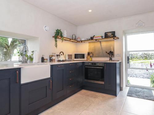 a kitchen with black and white appliances and a window at Meadow Syke Byre in Penrith