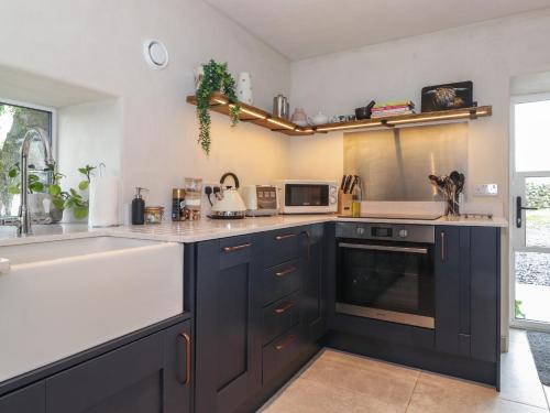 a kitchen with black cabinets and a white sink at Meadow Syke Byre in Penrith