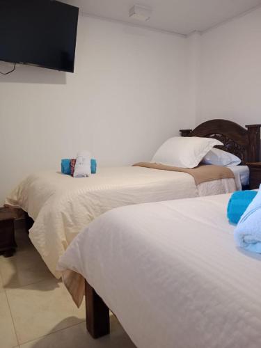 two beds in a room with a tv on the wall at Hotel Cafetero Valparaíso in La Vega
