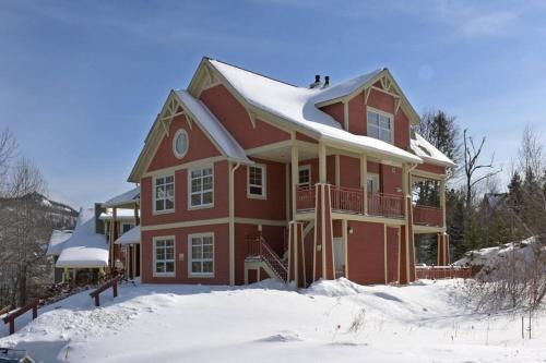 a large red house with snow on the roof at Les Eaux Tremblant Classic Chalet Pool & Jacuzzi in Mont-Tremblant